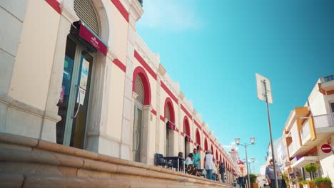 Portugal-Algarve-Loule-Traditionelle-Marktfassade,-Steinstraße-Mit-Fußgängern,-Terrassen-Bei-Morgensonne-4k