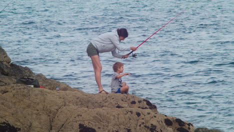 Un-Vínculo-Entre-Madre-E-Hijo-Mientras-Pescan-En-Las-Rocas-En-Cornualles,-Inglaterra