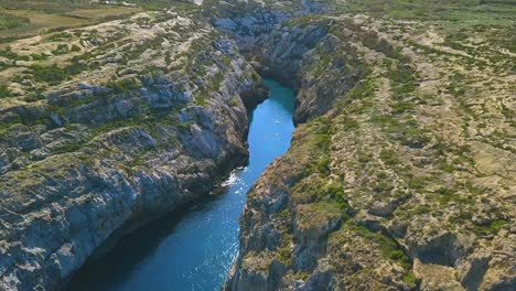 Arial-shot-of-Wied-Il-Ghasri,-a-secluded-inlet-with-a-tiny-pebbly-beach-wedged-between-high-cliffs-on-the-island-of-Gozo-in-Malta