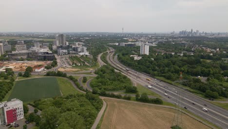 Luftaufnahme-Des-Dichten-Verkehrs-Auf-Der-Deutschen-Autobahn-A66-Mit-Dem-Stadtbild-Von-Frankfurt-Am-Main-Im-Hintergrund