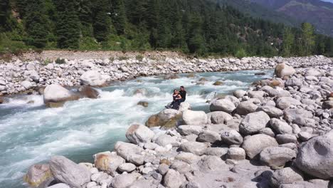 Aerial-shot-of-couple-in-black-dress-enjoying-water-stream-with-rocks