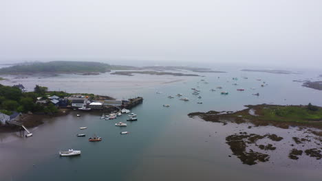 drone-aerial-of-lobster-fishing-boats-in-marina-ocean-bay-with-pier-and-islands-foggy-weather-4k-30p