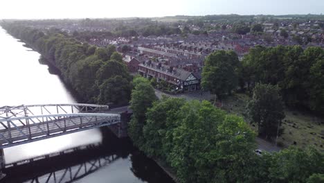 Aerial-view-Manchester-ship-canal-swing-bridge-orbit-across-Warrington-houses-England