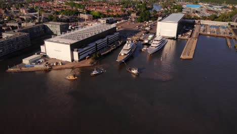 Luftaufnahme-Von-Schleppern,-Die-Einer-Luxusyacht-Beim-Anlegen-Am-Yachthafen-Der-Oceanco-Werft-In-Alblasserdam-Helfen