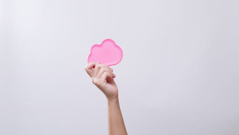 Woman's-hand-shows-a-cloud-icon-color-pink-symbol-in-white-studio-background-with-copy-space