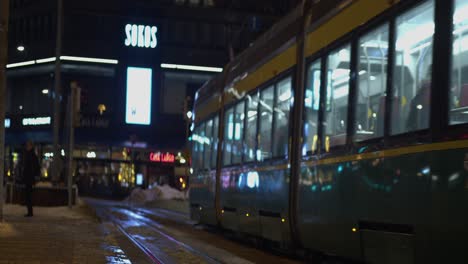 Narrow-focus-urban-transit-train-in-shopping-district-on-winter-night