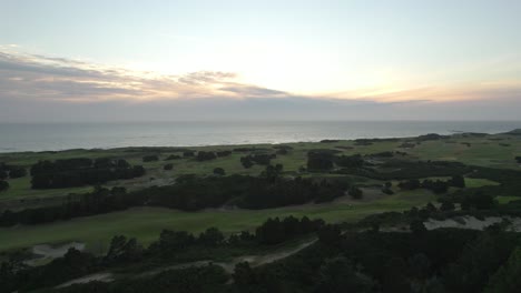 Aerial-view-of-sunset-above-Pacific-Ocean-and-Bandon-Dunes-Golf-Resort-in-Oregon,-USA