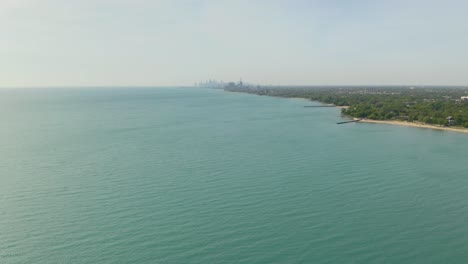 Drohne-Fliegt-über-Die-Blauen-Gewässer-Des-Michigansees-Mit-Der-Skyline-Von-Chicago-In-Der-Ferne