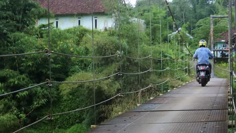 Puente-Colgante-Sobre-El-Río-Con-Cruce-De-Motocicletas-Por-La-Mañana-En-Sukabumi,-Java-Occidental,-Indonesia-El-4-De-Mayo-De-2022