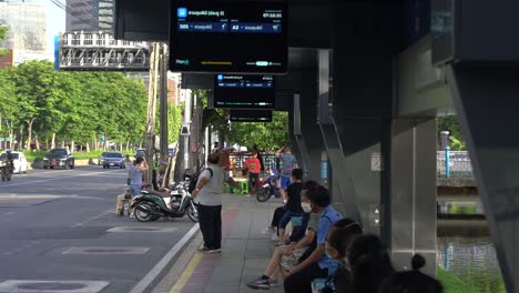 People-waiting-for-bus-outside-Lumpini-Park,-downtown-Bangkok