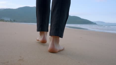 Cerca-De-Los-Pies-De-Un-Hombre-Caminando-Por-La-Playa-Bajo-El-Hermoso-Sol