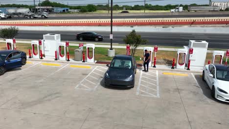 Person-Nutzt-Tesla-Ladegerät,-Um-Die-Batterie-Eines-Elektrofahrzeugs-Aufzuladen