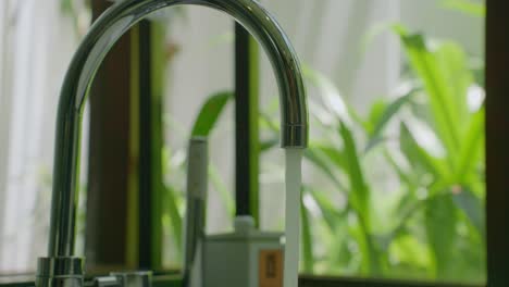 Close-up-a-beautiful-faucet-in-the-bathroom-with-a-background-full-of-green-trees