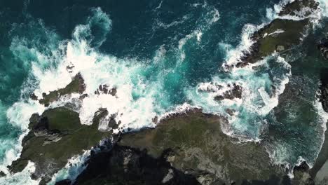 Sliding-overhead-shot-of-sea-waves-hitting-boulder-and-rocks-in-the-beach-in-sunny-condition-weather---Pengilon-Hill,-Yogyakarta,-Indonesia,-Asia