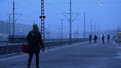 Few-passengers-on-snowy-train-station-platform-on-northern-winter-day