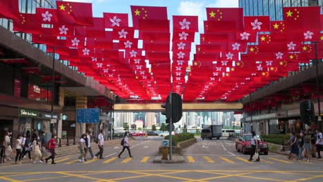 People-cross-the-street-as-flags-of-the-People's-Republic-of-China-and-the-Hong-Kong-SAR-are-displayed-ahead-of-July-1st-anniversary-of-Hong-Kong's-handover-to-China-in-Hong-Kong