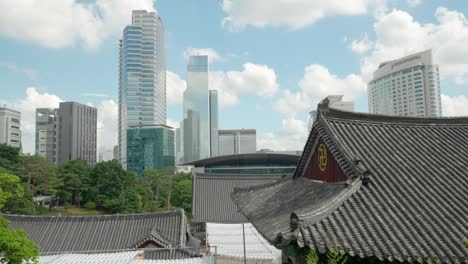 Bongeunsa-Temple-tiled-roofs-and-clouds-moving-and-reflecting-in-COEX-Business-District-buildings-in-Gangnam,-Seoul-on-sunny-summer-day