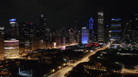 Una-Toma-Aérea-Revela-El-Horizonte-De-Chicago-Iluminado-En-Azul-Y-Rojo-Por-La-Noche.