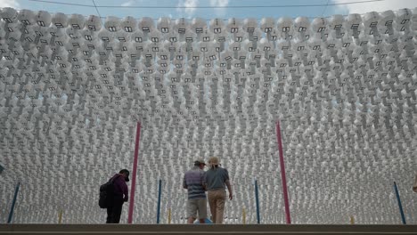 Templo-Bongeunsa---Pareja-De-Mediana-Edad-Subiendo-Las-Escaleras-Bajo-Filas-De-Faroles-De-Papel-Redondos-Blancos-Clásicos-Con-Tarjetas-De-Bendición-Colgadas-En-Línea-Para-Decoración-En-Un-Evento-De-Celebración