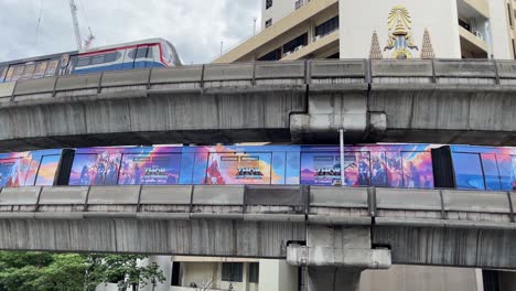 Two-BTS-trains-travelling-opposite-direction-,-elevated-tracks-downtown-Bangkok