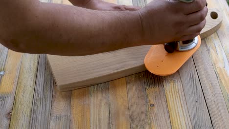 Cutting-edges-on-the-wooden-cutting-board-with-handheld-router-on-the-wooden-table