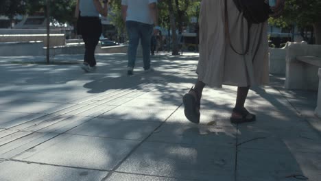 Woman-walks-across-the-frame-sits-on-park-bench