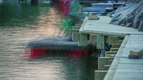 Static-shot-of-men-at-work-constructing-wooden-pier-on-a-rocky-shore-in-timelapse