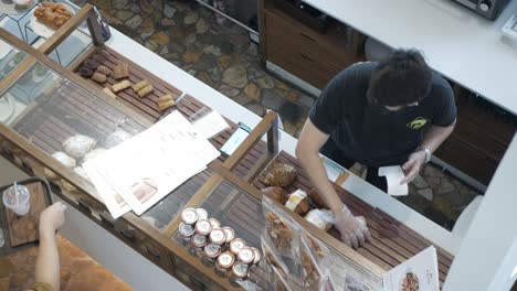 Vea-El-Interior-De-La-Cafetería-Mínima-Mientras-El-Personal-Hace-Su-Trabajo-Preparando-Pastelería-Y-Panadería.