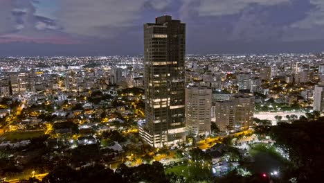 Aerial-view-around-the-Anacaona-27-tower,-dusk-in-Mirador-Del-Sur,-Santo-Domingo,-Dominican-Republic---orbit,-drone-shot