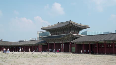 Gyeongbokgung-Palace---The-Geungjeongmun,-third-gate-to-the-courtyard-and-the-throne-hall-in-summer-with-tourists-in-hanboks-touring