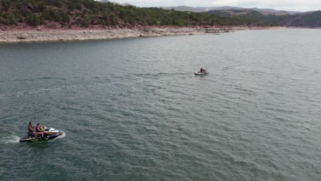 Waverunner-Jet-Ski-Riders-on-Fun-Summer-Day-at-Flaming-Gorge-Lake-Reservoir,-Aerial-Slow-Motion