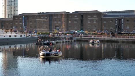 Canary-Wharf,-London,-United-Kingdom---August-2022---Two-floating-rings-with-a-BBQ-in-the-middle-are-drifting-slowly-in-the-canal-in-the-beautiful-and-warm-sunset-during-summer-in-London