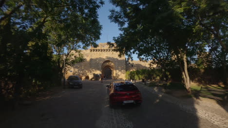 Aerial-follows-red-Mazda-as-it-approaches-old-castle-ruin-in-Spain