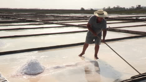 Marnoto,-Hombre-Trabajando-En-La-Salina,-Recoge-Sal-Del-Agua-Salada.