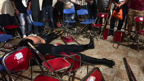 Freestyle-Wrestling-Indoor-Show-Performance,-Strong-Male-Wrestler-Ejected-on-other-Fighter-Sitting-on-Chair-During-Fighting-Battle,-People-Spectators-Audience-Around-Watching,-Mexican-Wrestling