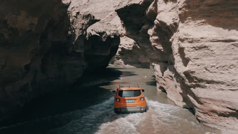 Offroad-Suv-Jeep-Renegade-Longitud-Conduciendo-En-El-Río-Cañón,-Tiro-De-Seguimiento-Aéreo