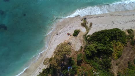 Toma-De-Drone-De-Una-Playa-Albanesa---Drone-Está-Descendiendo-A-Vista-De-Pájaro,-Acercándose-A-Una-Sombrilla