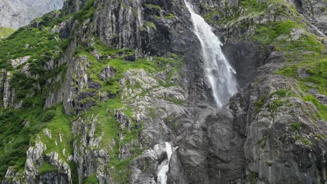 huge-waterfall-aerial-view-by-drone-from-underneath,-step-and-green-mountain-face,-Alps,-Switzerland,-Obwalden