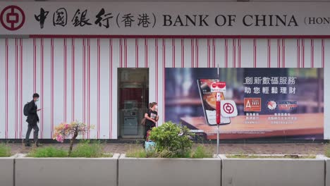 Chinesische-Fußgänger-Und-Pendler-Laufen-An-Dem-In-Hongkong-Ansässigen-Bank--Und-Finanzdienstleistungsunternehmen-Und-Dem-Hauptindikator-Für-Den-Hongkonger-Aktienmarkt,-Der-Hang-Seng-Bank-Und-Einer-Filiale-In-Hongkong-Vorbei