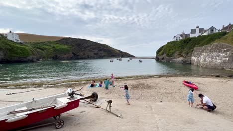 People-enjoying-the-cute-sandy-beach-of-fishing-village-Port-Isaac-in-Cornwall---British-coast,-United-Kingdom