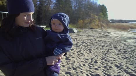 Bleiben-Sie-Zu-Hause,-Mutter-Und-Kinder-Genießen-Das-Sonnenlicht-Am-Strand-An-Einem-Kalten,-Sonnigen-Herbsttag