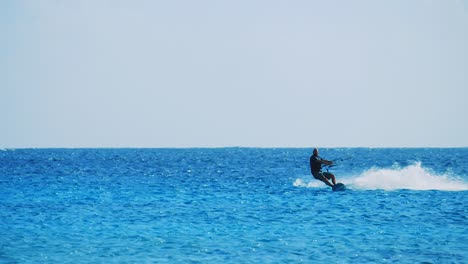 Slow-motion-shot-of-a-lone-kite-surfer-skimming-across-the-ocean-in-Bonaire,-Caribbean