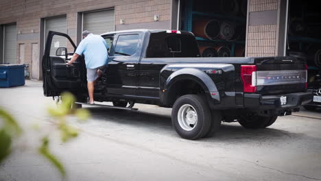 Man-entering-his-pickup-truck-and-driving-away-behind-a-warehouse