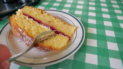 Footage-showing-a-slice-of-Victoria-Sponge-cake,-then-slowly-a-fork-coming-into-view-to-break-a-piece-off-the-end