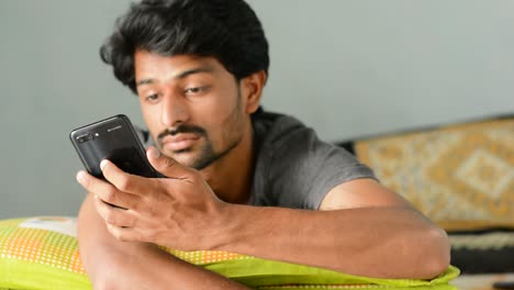 Indian-Teenager-sleeping-on-a-bed,-and-mobile-rings-he-checks-the-mobile-and-goes-back-to-the-sleep