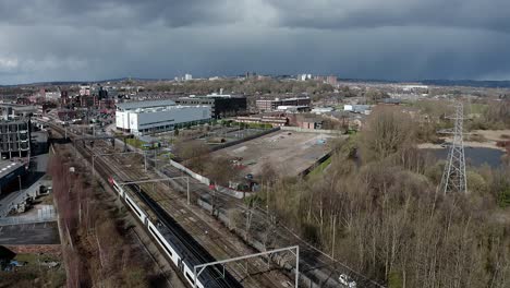 Imágenes-Aéreas-De-Trenes-Que-Se-Acercan-A-La-Estación-De-Tren-De-Stoke-On-Trent-En-Midlands-Junto-Al-Canal,-La-Orilla-Del-Agua-Y-La-Autopista-A50