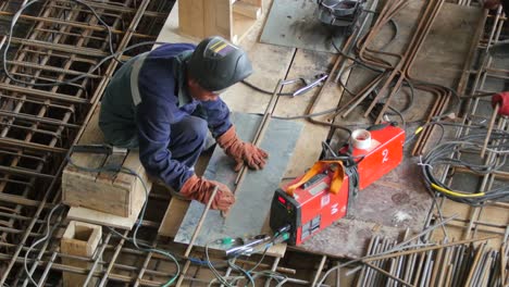 Un-Trabajador-Del-Hierro-Prepara-Barras-De-Acero-Para-Soldar-En-Un-Sitio-De-Construcción-Industrial