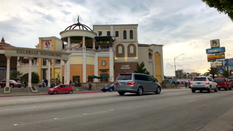 Street-scene-and-traffic-in-front-of-modern-shopping-mall-with-American-Brand-names,-Tijuana-Mexico