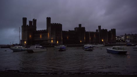 Pequeños-Barcos-Flotando-En-El-Puerto-Frente-Al-Histórico-Castillo-De-Caenarfon-Al-Atardecer-En-Aguas-Agitadas-Justo-Cuando-Una-Tormenta-Estaba-A-Punto-De-Comenzar