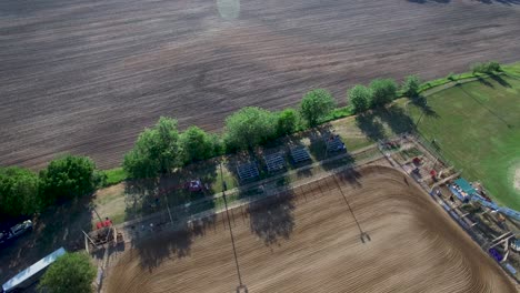 Retiro-Aéreo-Desde-Un-Campo-En-Barbecho-Para-Revelar-El-Tractor-Verde-Que-Prepara-El-Campo-De-Caballos-De-Tierra,-Kansas,-Missouri